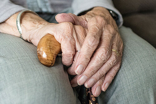Hands of elderly woman with walking stick